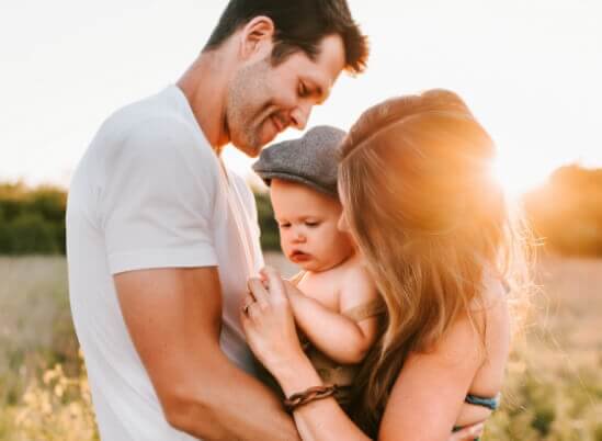 Couple with baby outside at sunset
