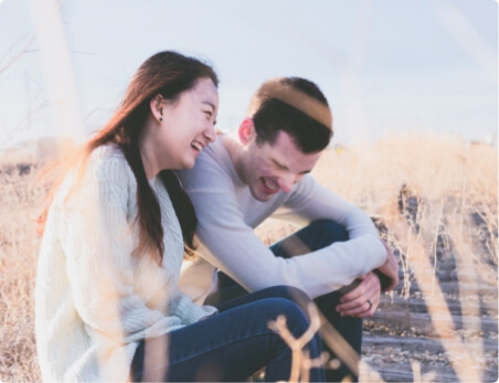 couple sitting in dry grass and laughing