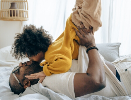 Father playing with child on a bed