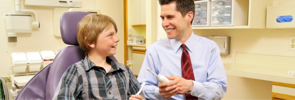 Dr. Christopher talking to a child about tooth brushes